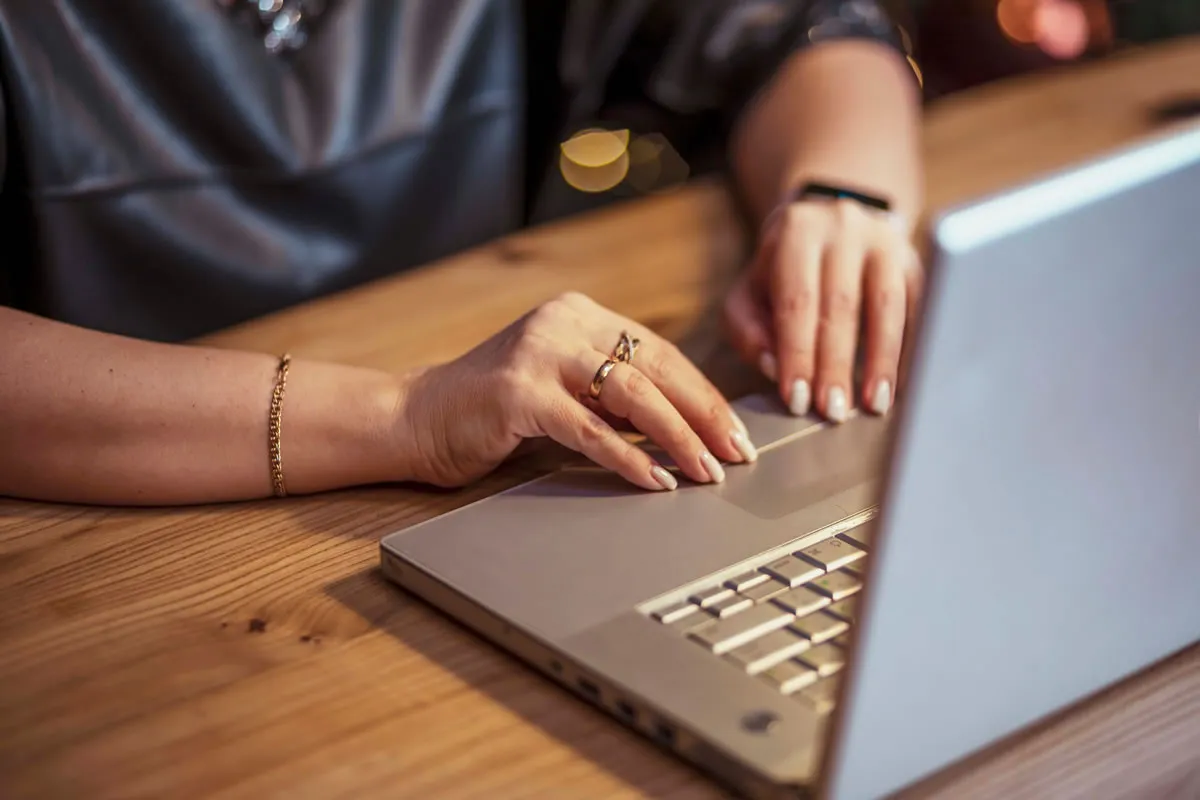 Mãos digitando em um notebook ao otimizar o conteúdo de um site